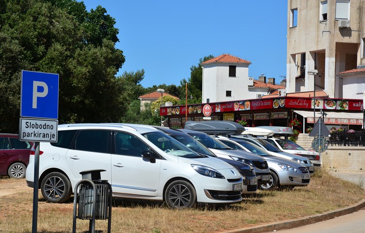Velik broj automobila parkiran je na zemljanim površinama oko naselja